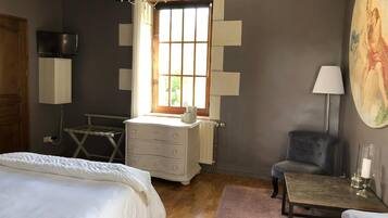 A bedroom with a bed, dresser, chair, and a table with a lamp.