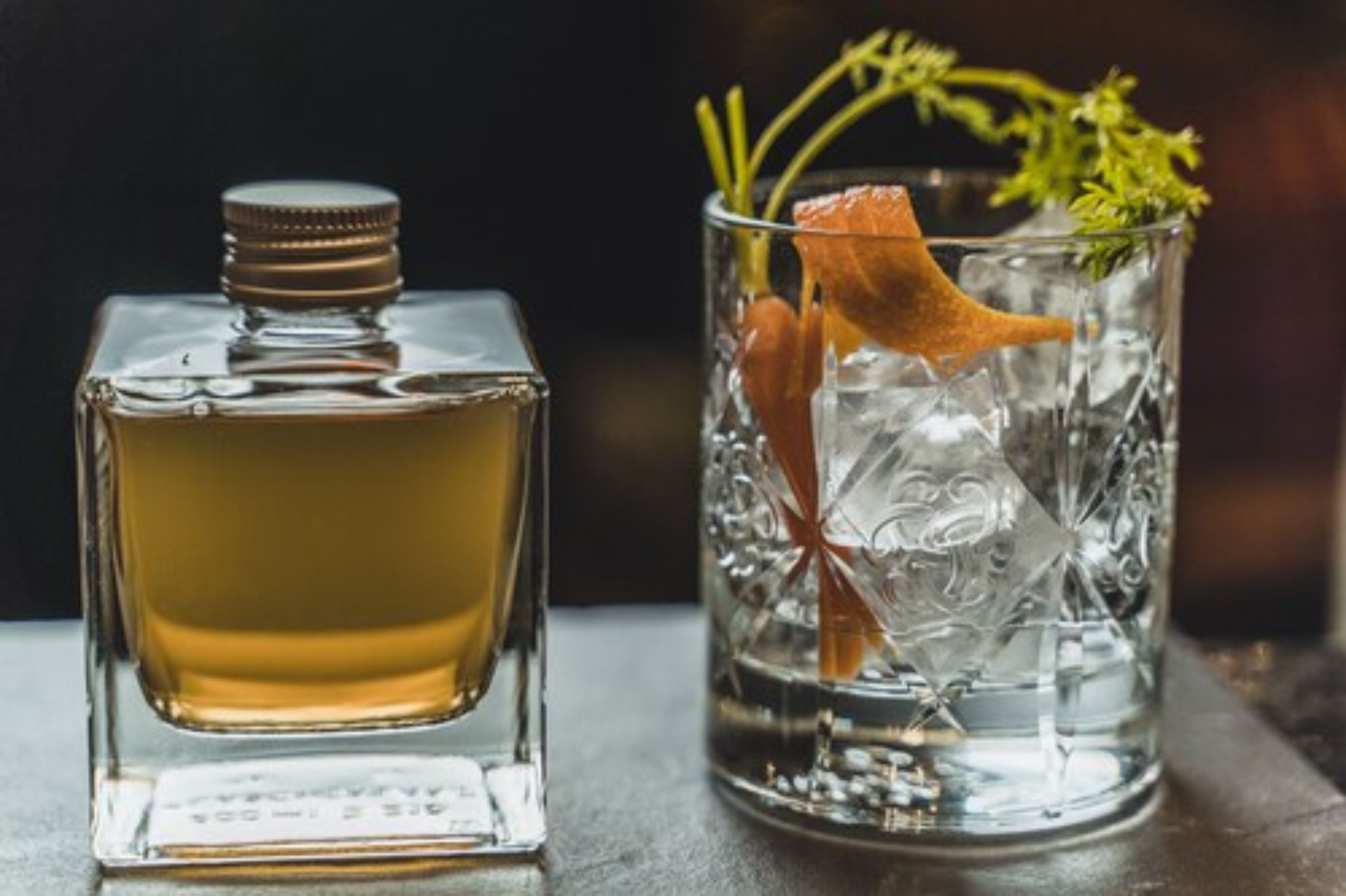 Eine Parfumflasche und ein Glas mit Eiswürfeln und einer Blume.