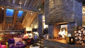 Un intérieur chaleureux avec une cheminée en pierre, des poutres apparentes et un coin salon confortable.