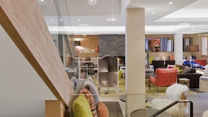 Un intérieur moderne avec un escalier en verre, un coin repas et un espace salon offrant une vue sur la salle à manger.