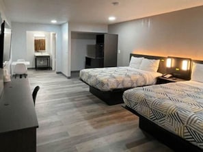 Ett hotellrum med två sängar, ett skrivbord, en tv och ett badrum som syns i bakgrunden.