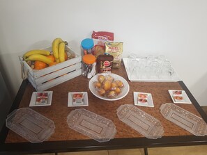 Een tafel met een fruitmand, sauzen en Helios vruchtensappen.