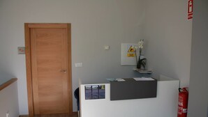 Un comptoir d’accueil avec une porte en bois, un extincteur et une petite plante.