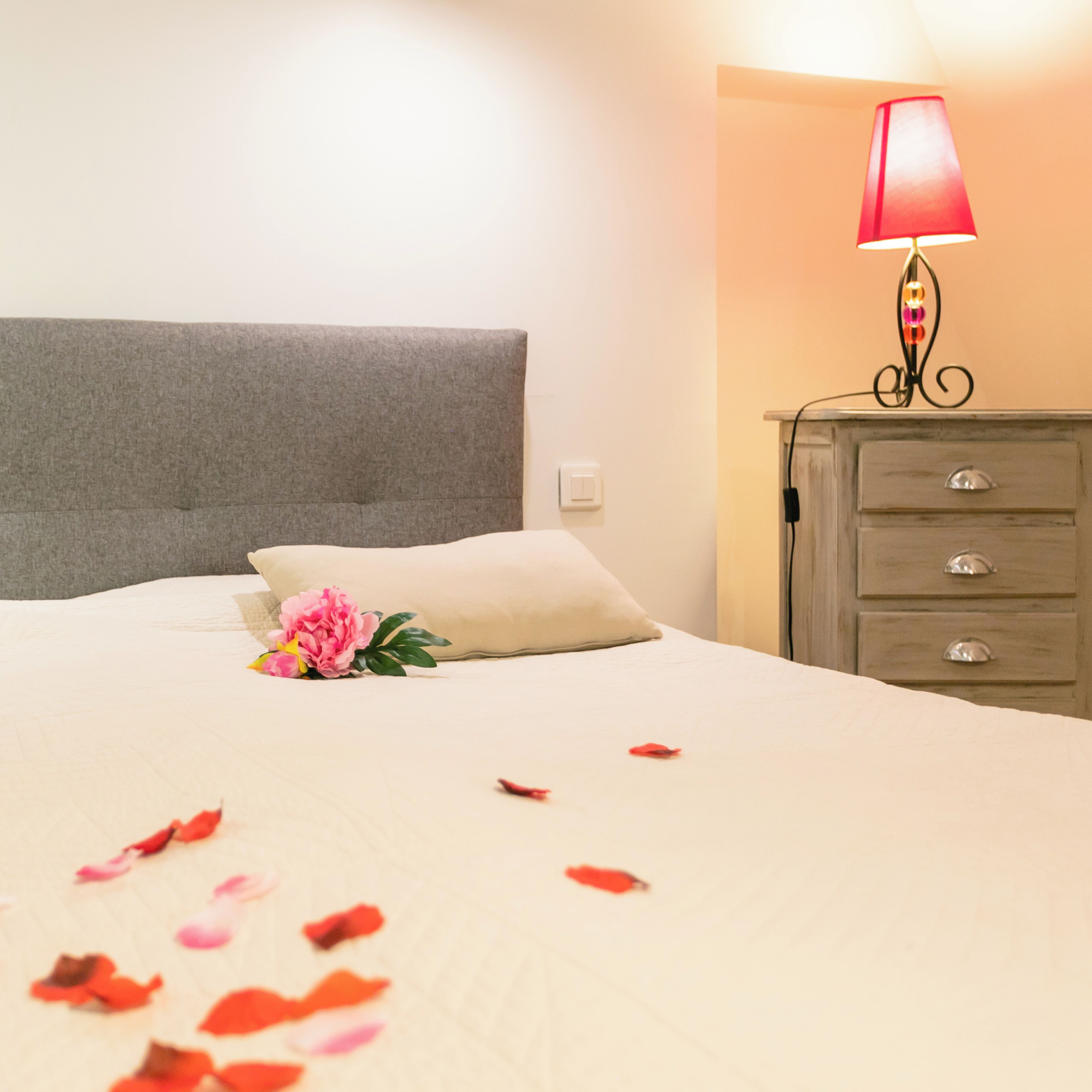 A neatly made bed with a pillow, a bedside lamp, and a dresser with drawers.