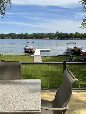 A lakeside deck with two boats docked, a flag, and a grassy area. - Lakehouse with Pontoon, Deck, Firepit, Paddle Boards, Grill & more INCLUDED!!  (Valparaiso)