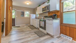 A kitchen with wooden cabinets, a microwave, stove, and a refrigerator. - Lakehouse with Pontoon, Deck, Firepit, Paddle Boards, Grill & more INCLUDED!!  (Valparaiso)