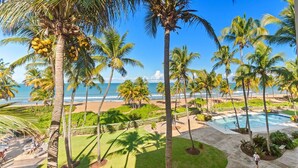 Un resort con piscina, palmeras y vista al mar.