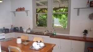 Eine kompakte Küche mit weißen Schränken, einem Holztisch, einer Bar und einem Fenster mit Blick auf Grünflächen.