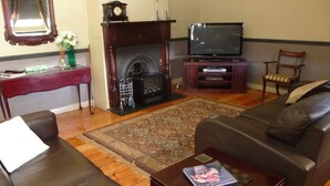 Ein Wohnzimmer mit Kamin, Fernseher, Sofa und Couchtisch.