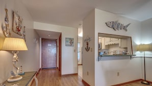 Un pasillo con suelo de madera, decoración de temática náutica, un espejo y una lámpara.
