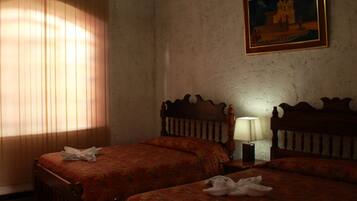 Habitación de hotel con dos camas, una mesita de noche con lámpara y un cuadro en la pared.