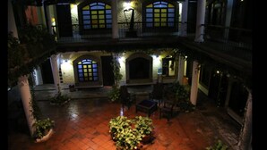 A courtyard with a central seating area, arched windows, and a stone fireplace. - Hotel Alcazar De Doña Victoria (Cobán)