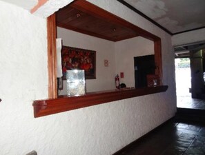 Ein Empfangsbereich mit Holztresen, einem gerahmten Bild an der Wand und einem Feuerlöscher.