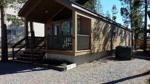 A single-story mobile home with a porch, a small set of stairs, and a gravel driveway.