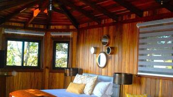 Une pièce de style cabane en bois, avec un lit, un canapé et un ventilateur de plafond.