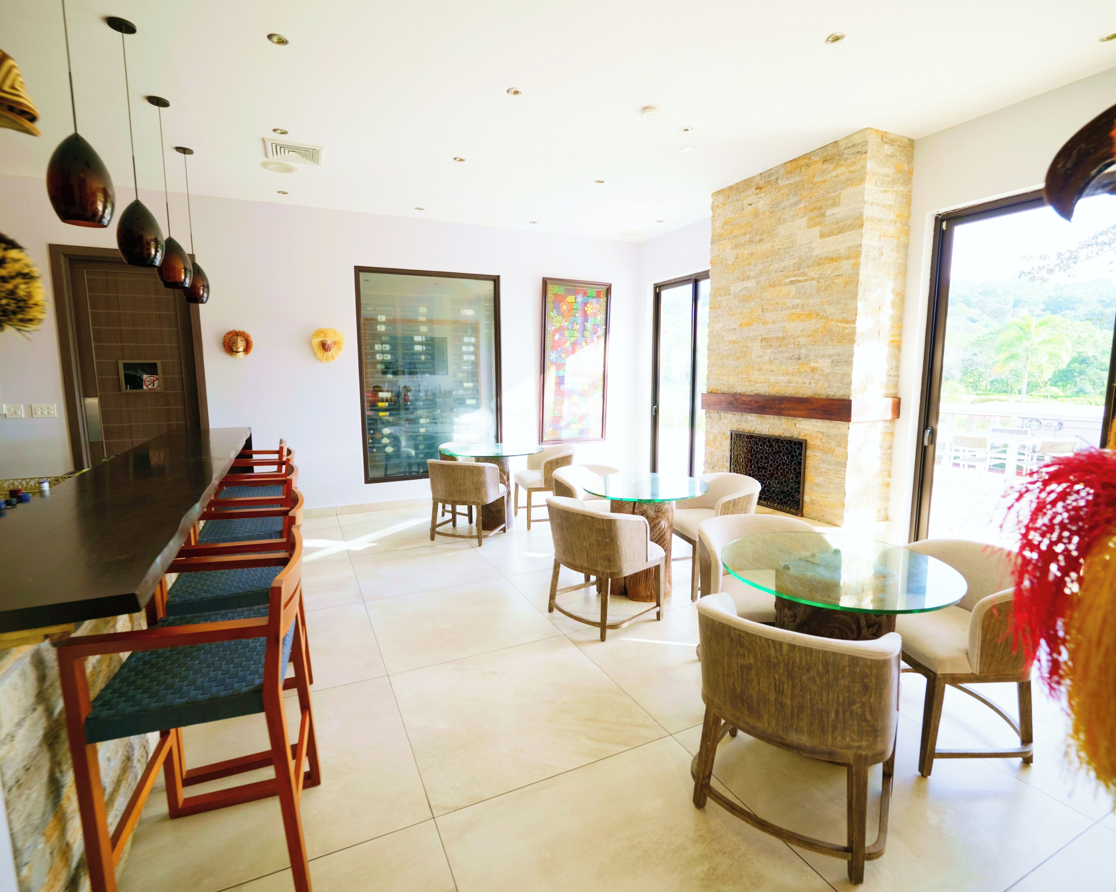 A modern dining area with a glass table and chairs, a stone accent wall, and a view of the outdoors.