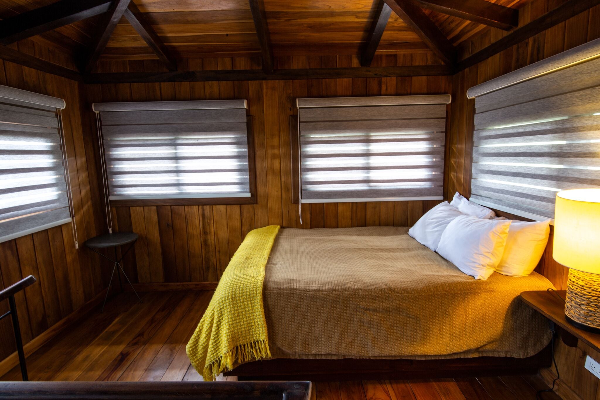 A wooden cabin bedroom with a bed, a bedside lamp, and a small table.