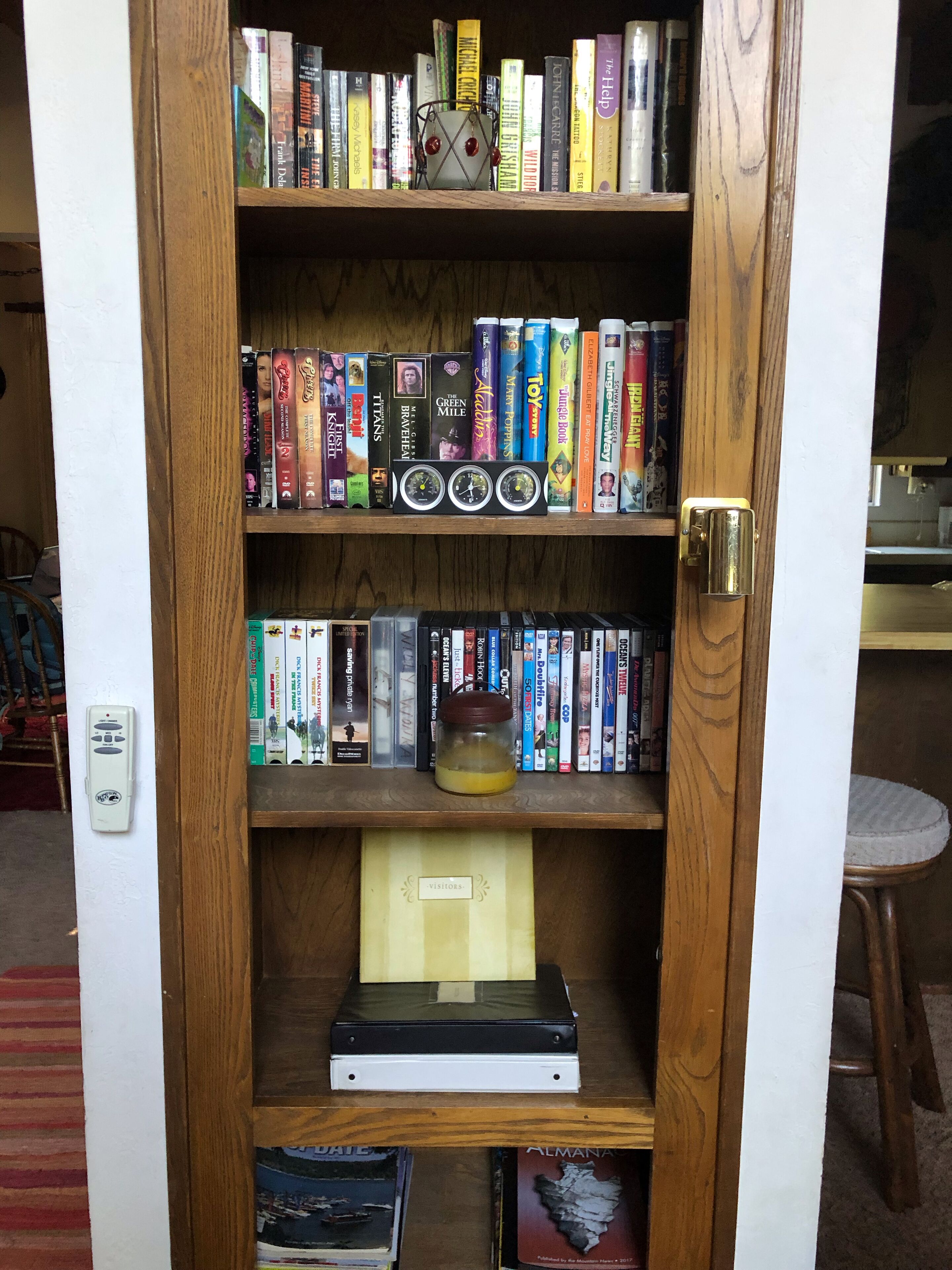 Une bibliothèque en bois contenant divers ouvrages, un petit objet décoratif et un livre d’or pour les visiteurs.