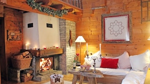A cozy log cabin interior with a stone fireplace, wooden furniture, and a decorative wall piece. - Charming lux chalet, views, comfort, escape, Samoens Valley, peaceful log fire (Mieussy)