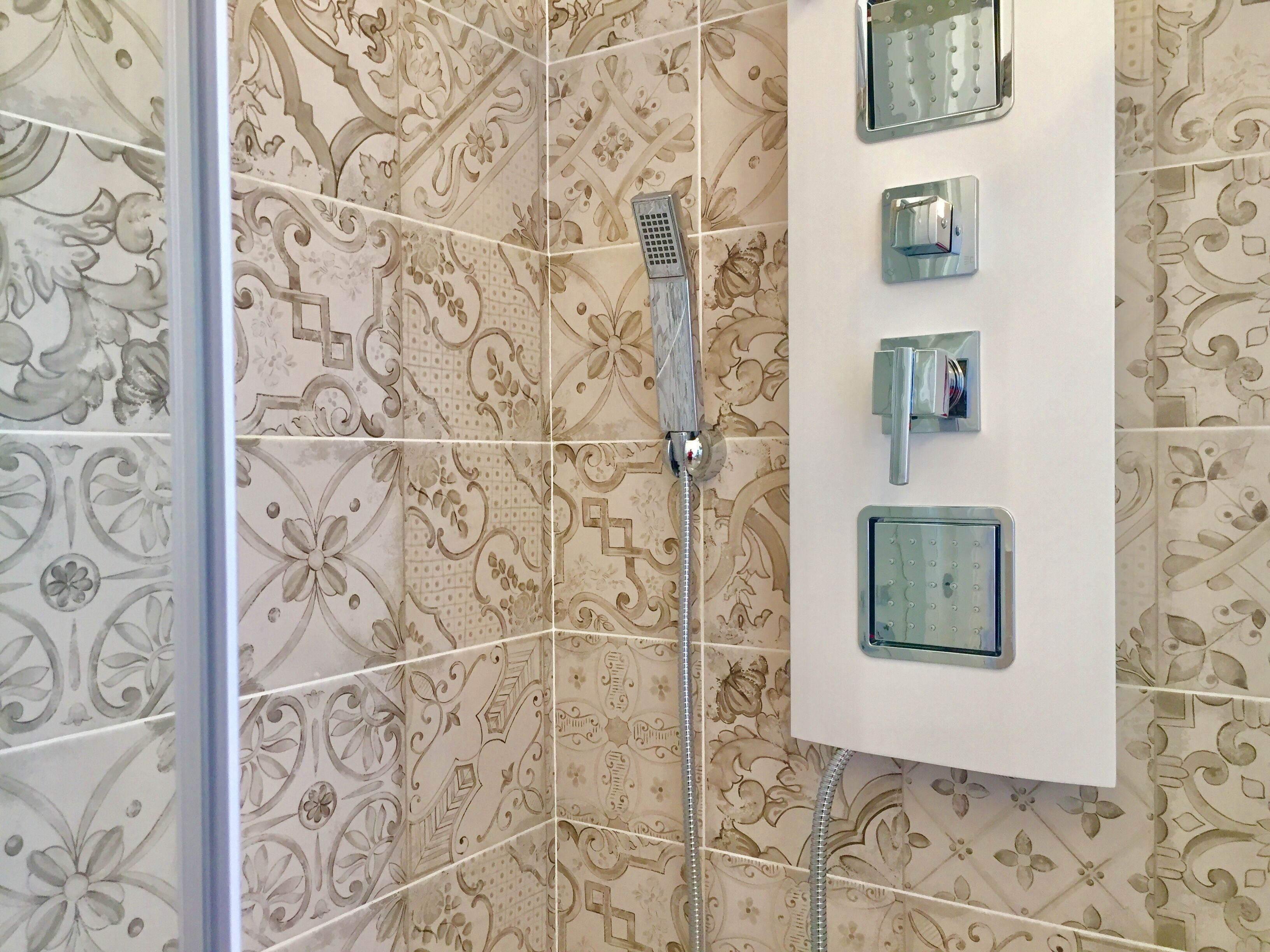 Une douche équipée d’un pommeau de douche à main et d’un panneau de commande mural doté de trois boutons.