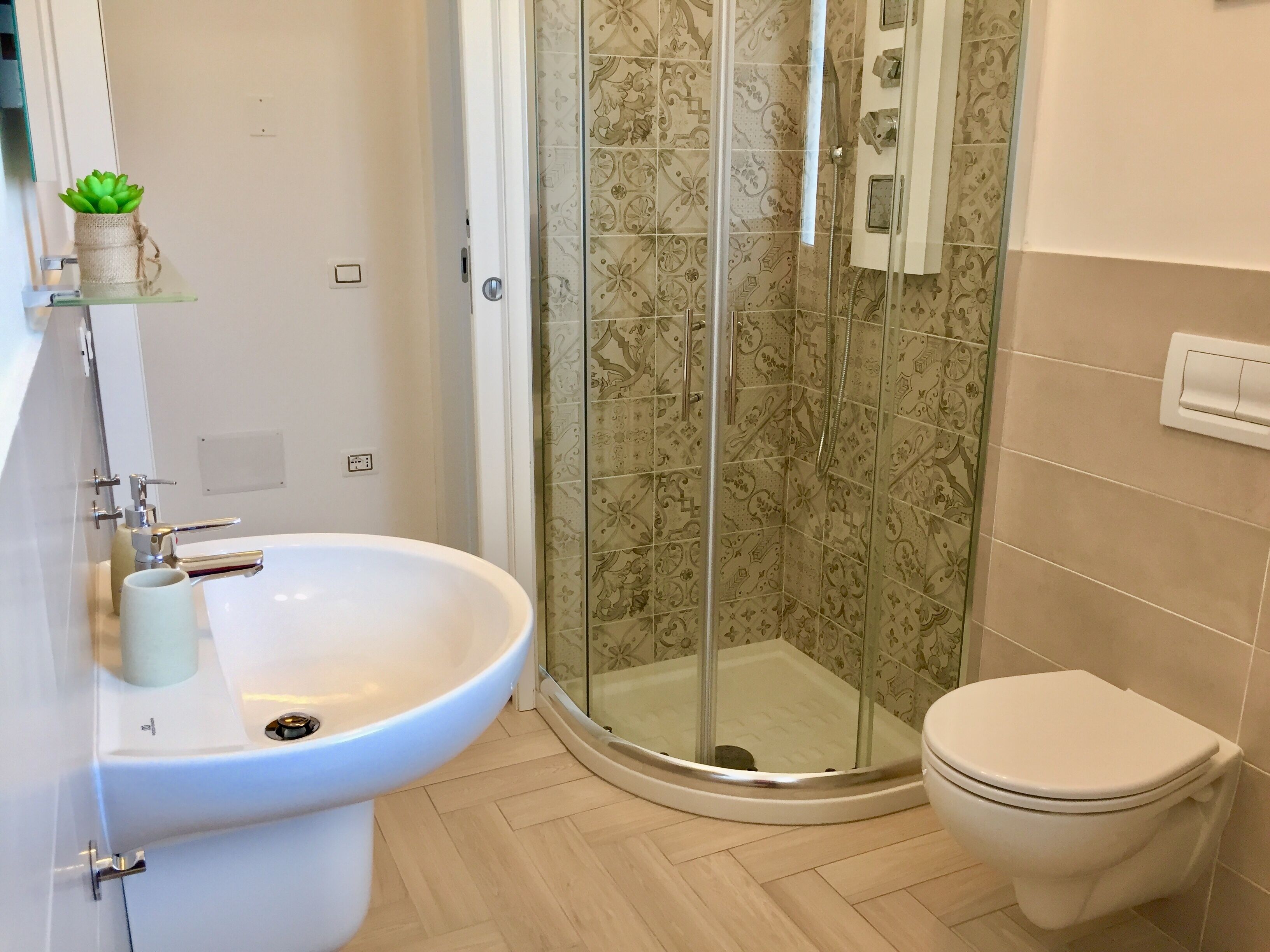 Un bagno con doccia vetrata, lavandino bianco e WC.
