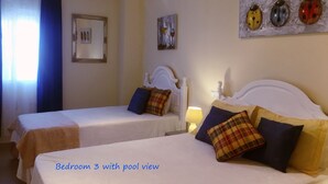 A bedroom with two beds, a view of the pool, and artwork on the walls.