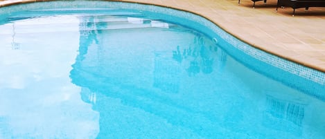 A swimming pool with lounge chairs and potted plants.