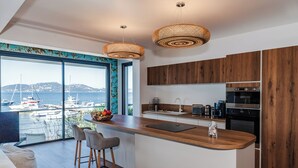 Eine moderne Küche mit einer großen Kochinsel, Holzschränken und Blick auf Boote in einer Marina.