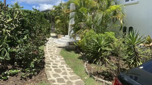 A stone pathway leading to a white building with a small garden and palm trees. - Villa, 4 beds, 3 bathrooms, 1 minute to beach by car or 10 minute stroll (Westmoreland)