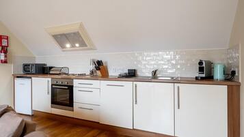 Eine kompakte Küche mit Mikrowelle, Toaster, Kaffeemaschine und einem kleinen Backofen.