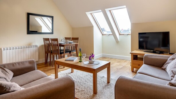 A modern living room with a dining area, a TV, and skylights. - A 2 bed apartment that sleeps 4 guests  in 2 bedrooms (kenmare)