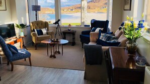 A living room with a large window, a telescope, and a view of a landscape. - Mellon Udrigle "Heaven on Earth",Luxury 6 bed Beach House, sea views (Scottish Highlands)