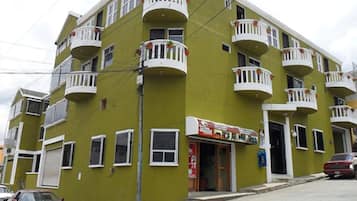Un edificio de varios pisos con balcones, una tienda y coches estacionados.
