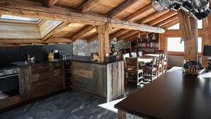 Eine rustikale Küche mit Holzbalken, einer großen Kochinsel und einer Steinwand.