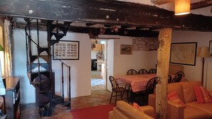 Een rustiek interieur met een trap, een eethoek en een woonkamer met een rood tapijt.