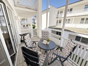 Un balcone con tavolo e sedie, ringhiere bianche e vista sui palazzi vicini.