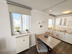 A modern kitchen with white cabinets, a wooden dining table, and a built-in oven. - P: Villa Karola Whg. 14 with balcony - Villa Karola Whg. 14 with balcony (Göhren)