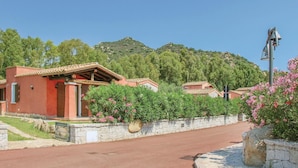 Un edificio con techo rojo, pared de piedra y una calle pavimentada al frente.