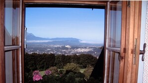 Ein offenes Fenster mit Blick auf eine Stadt und Berge in der Ferne.