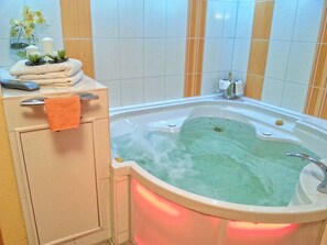 A bathroom with a bathtub, a towel rack, a glass of water, and a small plant. - Vacation dream: 30m to the beach, sea view, sauna, whirlpool, 2 bedrooms just luxury (Lübeck)