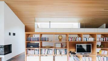 A modern living room with a wooden bookshelf, a flat-screen TV, and a fireplace.