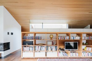 Un salon moderne avec une bibliothèque en bois, un téléviseur à écran plat et une cheminée.