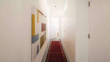 A hallway with a red carpet, white walls, and a door at the end.