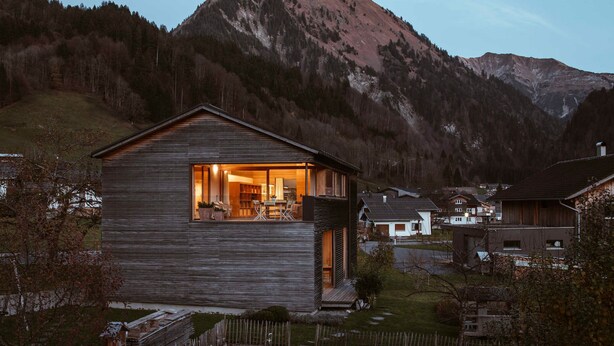 Une cabane en bois dotée d’un balcon, entourée d’un paysage montagneux.