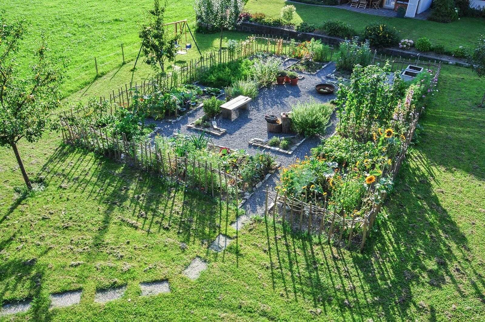 A garden with raised beds, a swing set, and a small seating area.