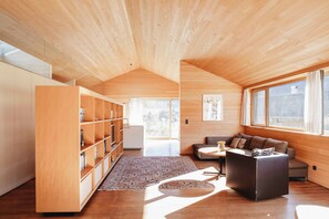 Un intérieur moderne avec des plafonds en bois, un canapé, une table basse et une bibliothèque.