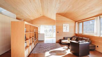 A modern interior with wooden ceilings, a sofa, a coffee table, and a bookshelf.