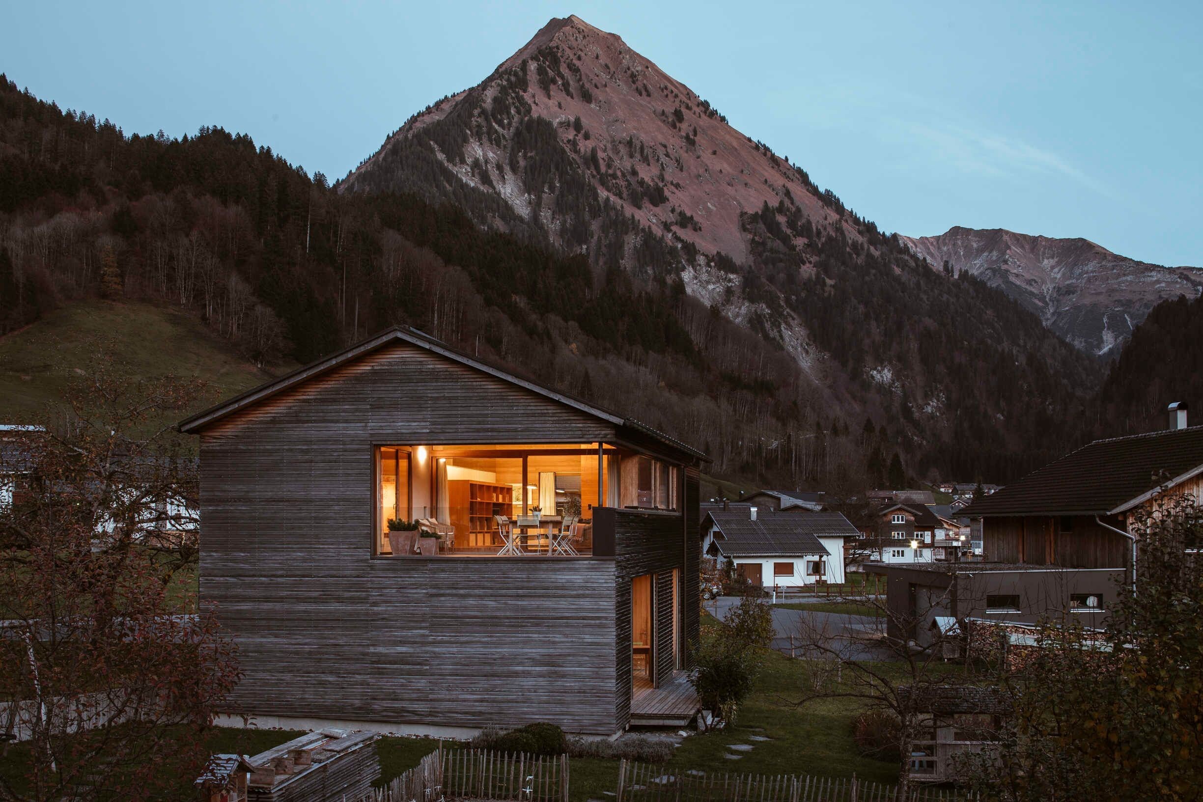 A wooden cabin with a balcony, surrounded by a mountainous landscape.