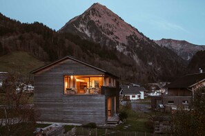 Een houten chalet met balkon, gelegen in een bergachtig landschap.