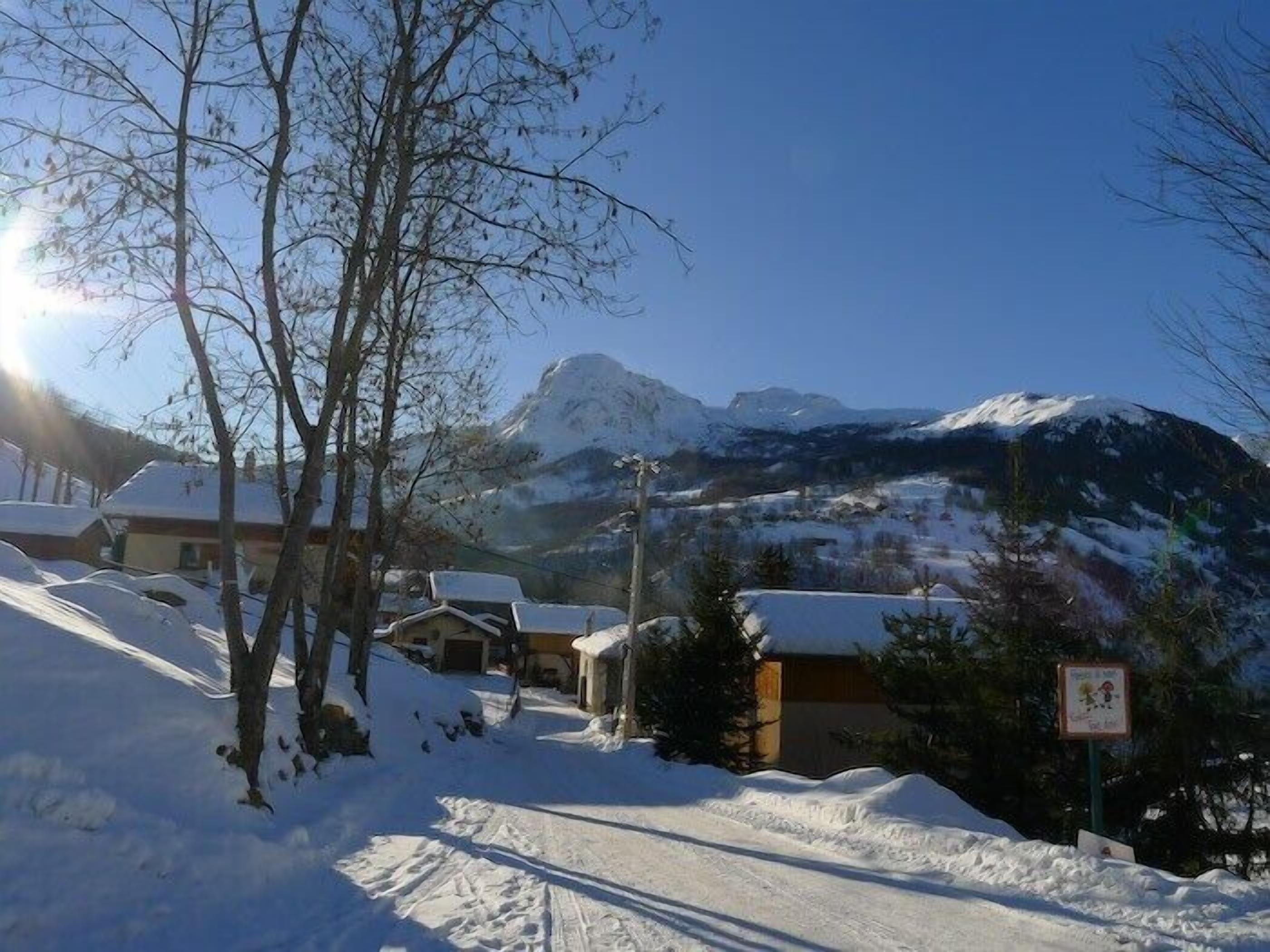 Un village enneigé, avec des maisons et une montagne en arrière-plan.